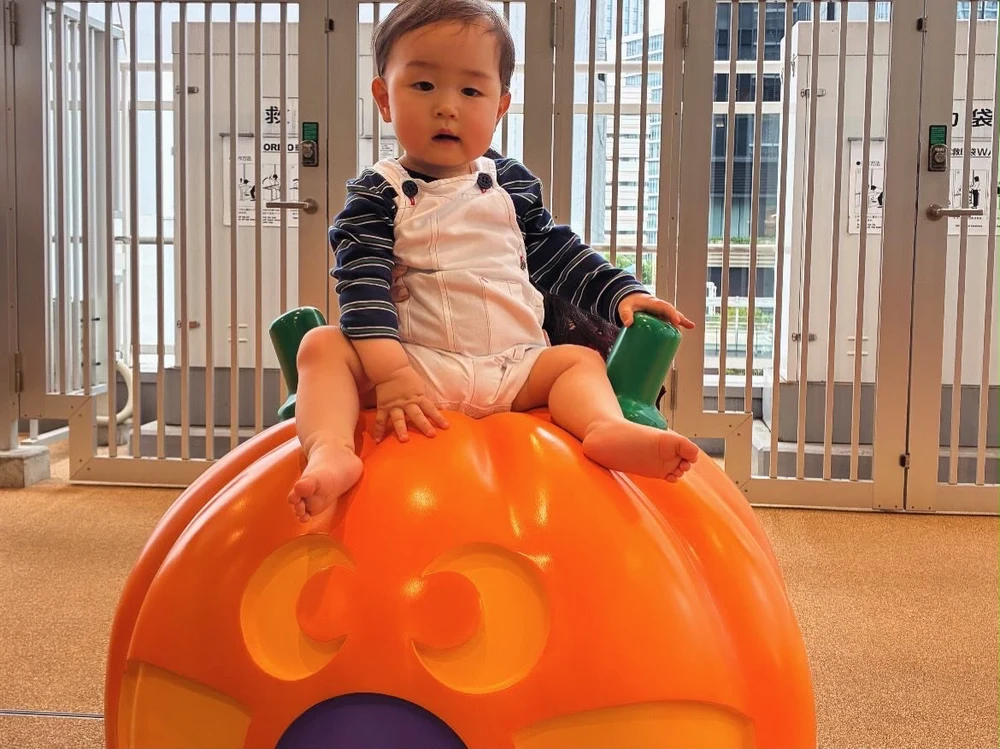 Bruno sentado em um brinquedo laranja